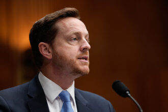 A Healthcare Administrator Reviewing Algorithmic Medicare Prior Authorization Decisions On A Computer